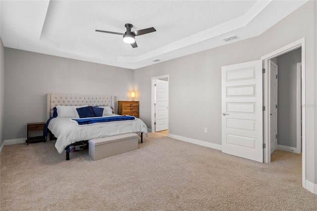 carpeted bedroom with a tray ceiling and ceiling fan