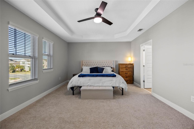 bedroom with a tray ceiling, ceiling fan, and light colored carpet