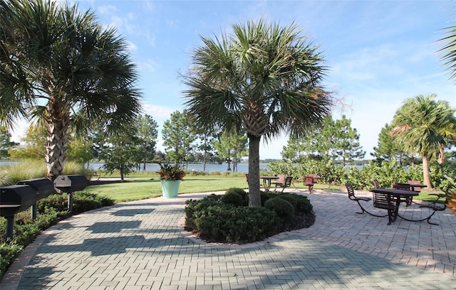 view of community with a patio, a water view, and a lawn