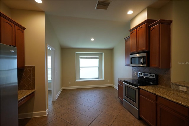 kitchen featuring vaulted ceiling, tasteful backsplash, light tile patterned floors, stainless steel appliances, and light stone countertops