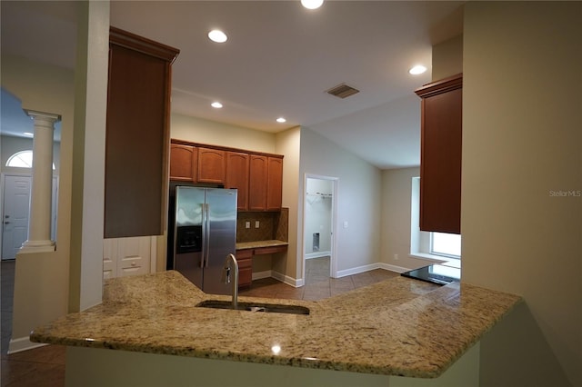 kitchen with stainless steel fridge with ice dispenser, decorative columns, sink, light tile patterned floors, and kitchen peninsula