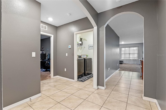 hall with separate washer and dryer and light colored carpet