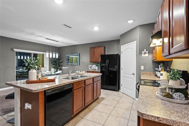 kitchen featuring a center island with sink, black appliances, hanging light fixtures, light tile patterned floors, and sink