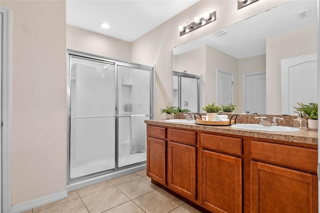 bathroom with a shower with door, vanity, and tile patterned floors