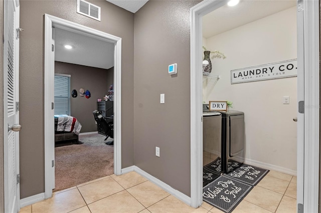 hall with washer and clothes dryer and light tile patterned floors