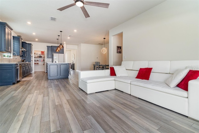 living room with light wood-type flooring and ceiling fan