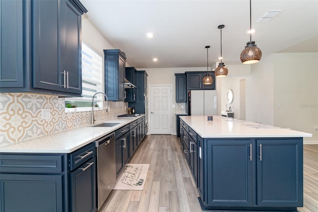 kitchen featuring decorative light fixtures, a center island, sink, blue cabinetry, and stainless steel appliances