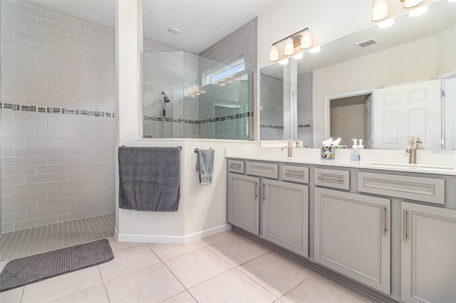 bathroom with tiled shower, vanity, and tile patterned flooring