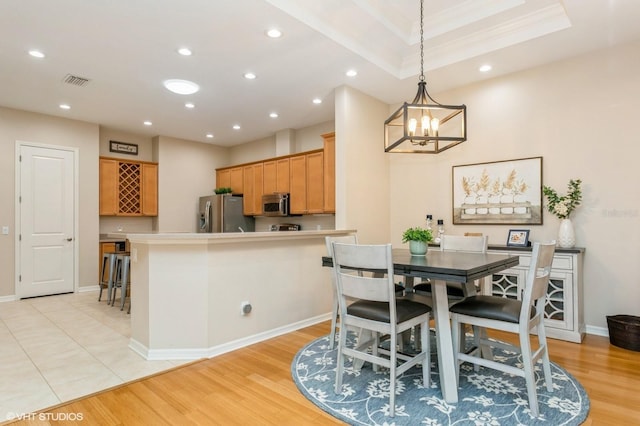 dining area featuring ornamental molding, a notable chandelier, and light wood-type flooring