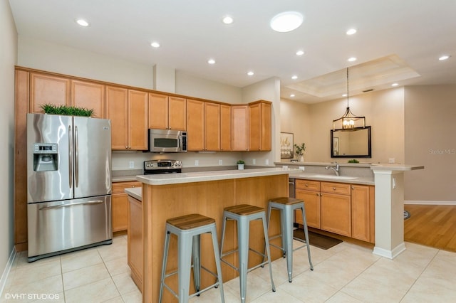 kitchen with a kitchen breakfast bar, stainless steel appliances, a raised ceiling, and a center island