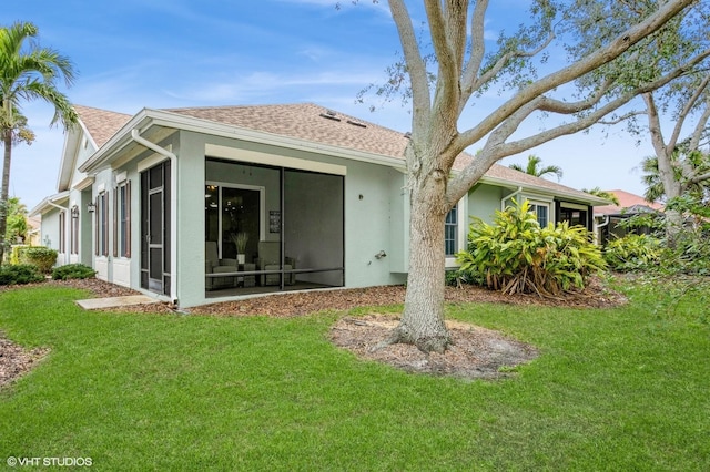 rear view of house with a sunroom and a lawn