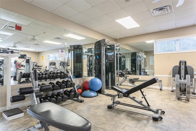 workout area featuring a paneled ceiling, plenty of natural light, and ceiling fan