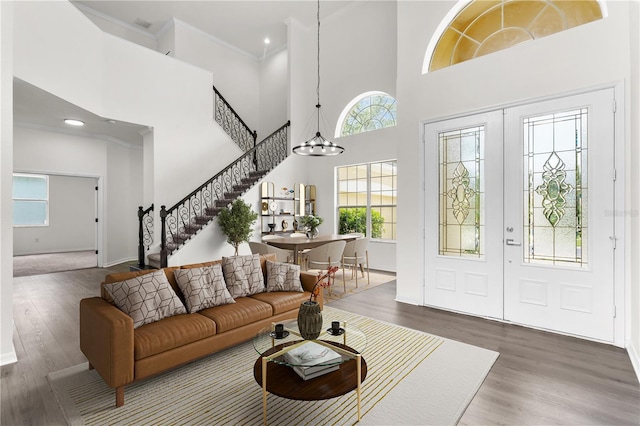 entryway with a chandelier, a towering ceiling, dark hardwood / wood-style floors, and crown molding