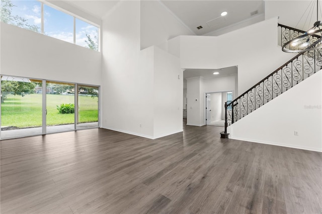 unfurnished living room featuring a high ceiling, dark wood-type flooring, and a notable chandelier