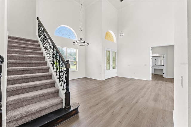 foyer with hardwood / wood-style flooring, a healthy amount of sunlight, a towering ceiling, and a chandelier