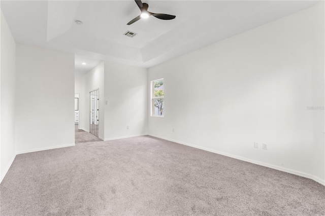 carpeted empty room with a tray ceiling and ceiling fan