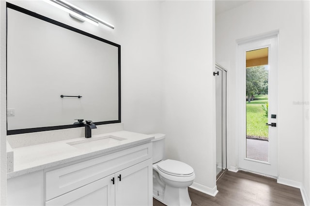 bathroom with hardwood / wood-style flooring, vanity, toilet, and a shower with shower door