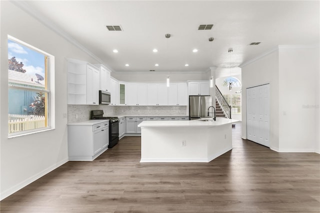 kitchen with appliances with stainless steel finishes, dark hardwood / wood-style flooring, pendant lighting, a center island with sink, and white cabinets