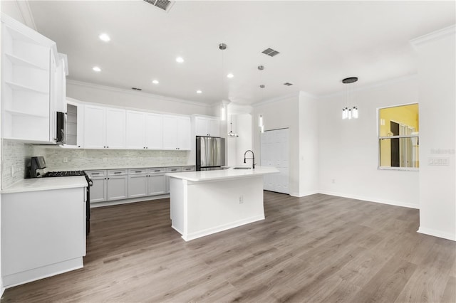 kitchen with stainless steel refrigerator, gas range gas stove, white cabinetry, hanging light fixtures, and a center island with sink