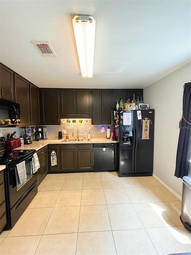 kitchen featuring a sink, decorative backsplash, black appliances, visible vents, and light countertops