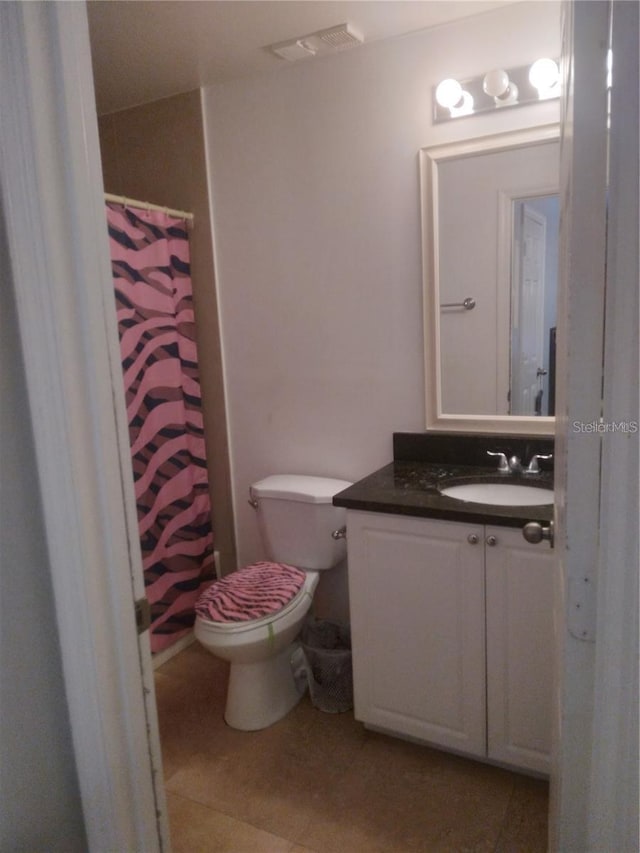 bathroom featuring curtained shower, visible vents, toilet, vanity, and tile patterned flooring