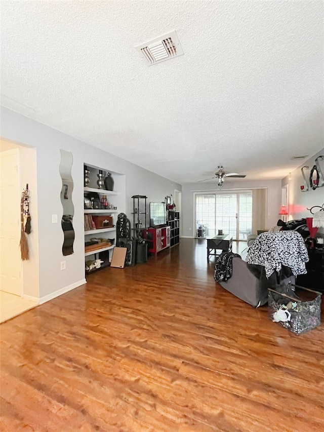 interior space featuring a textured ceiling, visible vents, wood finished floors, a ceiling fan, and built in features