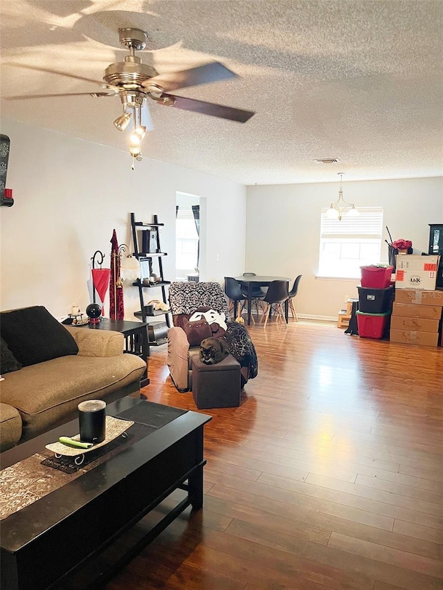 living area featuring a textured ceiling, wood finished floors, and a ceiling fan