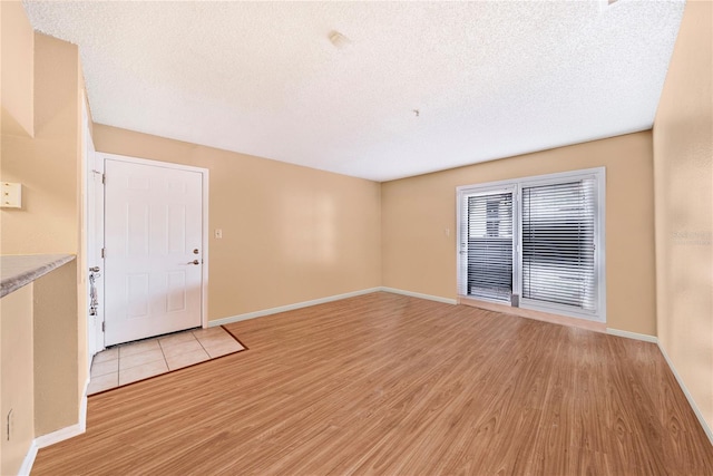 unfurnished living room with a textured ceiling and light hardwood / wood-style flooring