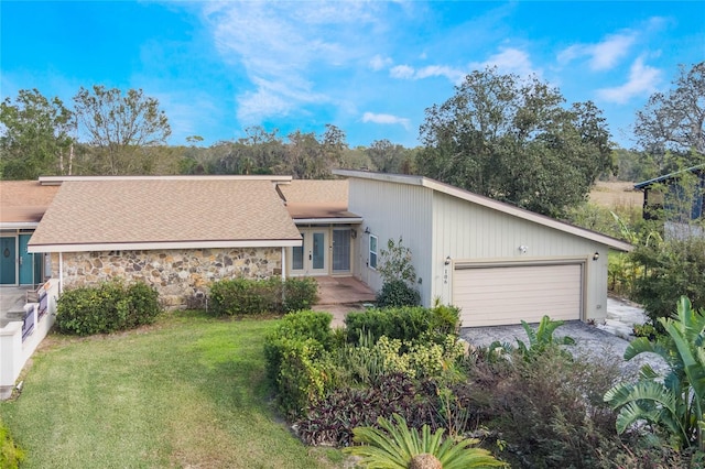 single story home with a garage, a front yard, and french doors