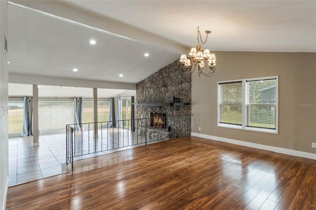 unfurnished living room with a stone fireplace, a healthy amount of sunlight, hardwood / wood-style floors, and lofted ceiling with beams