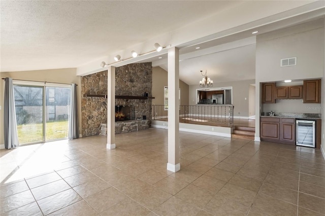 unfurnished living room with a fireplace, tile patterned flooring, vaulted ceiling, and beverage cooler