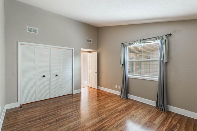 unfurnished bedroom featuring dark hardwood / wood-style flooring, a closet, and vaulted ceiling