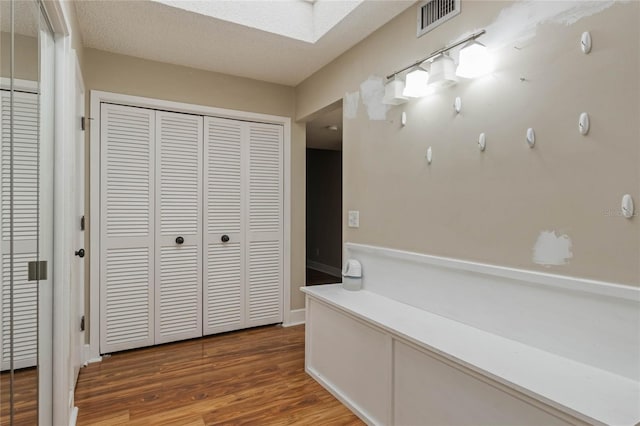 corridor with hardwood / wood-style flooring, a textured ceiling, and a skylight