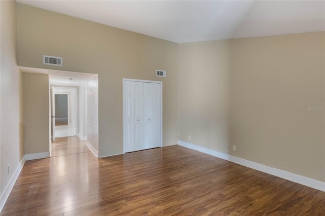 spare room with hardwood / wood-style floors and a high ceiling