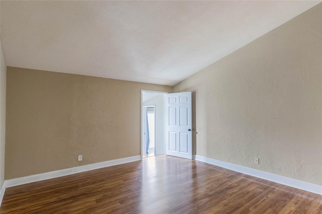 unfurnished room with hardwood / wood-style floors and lofted ceiling