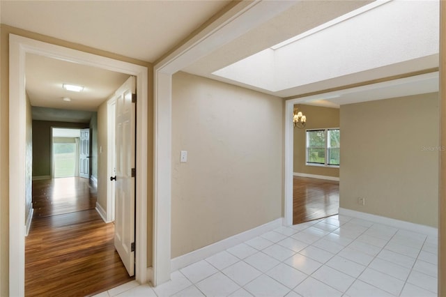 hall with light tile patterned flooring and a chandelier