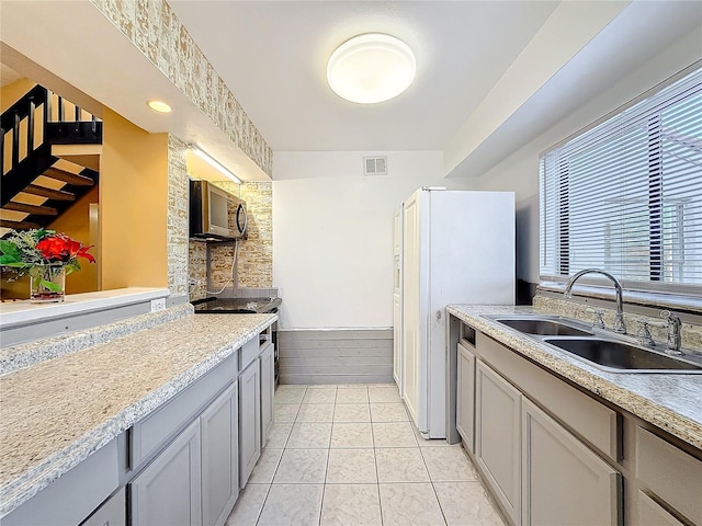 kitchen with gray cabinetry, sink, light tile patterned flooring, and white refrigerator