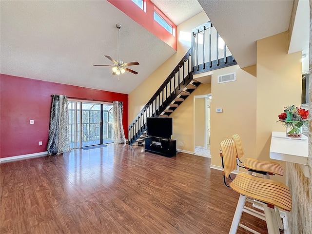 living room featuring ceiling fan, high vaulted ceiling, wood-type flooring, and a textured ceiling