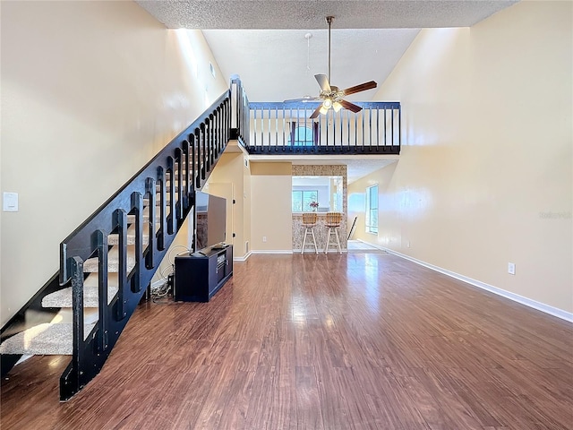 living room featuring ceiling fan, a towering ceiling, and hardwood / wood-style flooring