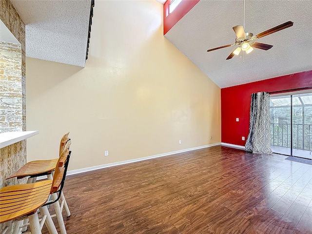 interior space featuring ceiling fan, dark hardwood / wood-style flooring, lofted ceiling, and a textured ceiling