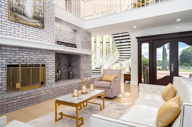 tiled living room featuring a towering ceiling, a fireplace, and french doors