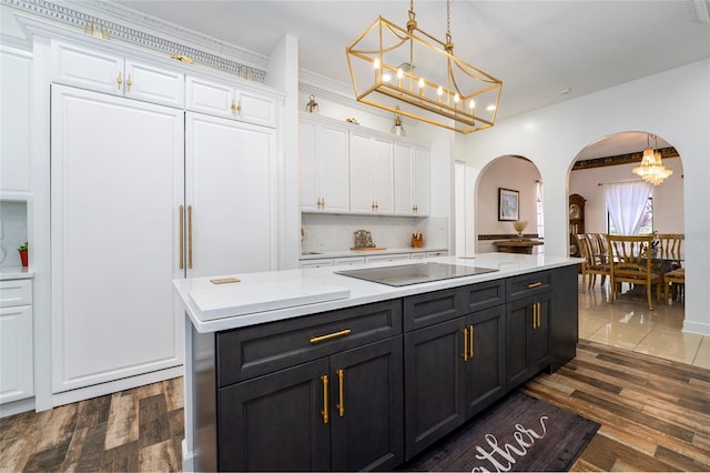 kitchen with tasteful backsplash, black electric cooktop, pendant lighting, white cabinets, and a kitchen island