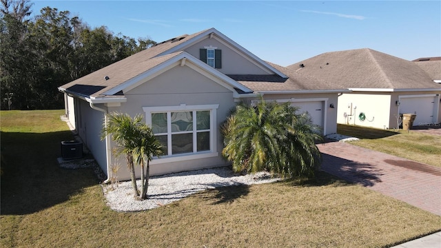 view of front of property featuring a garage, central air condition unit, and a front lawn