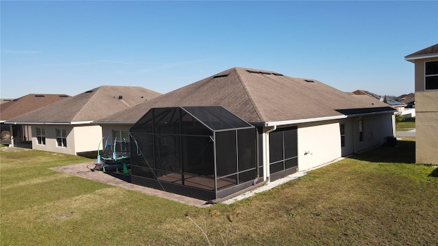 back of property with glass enclosure and a yard