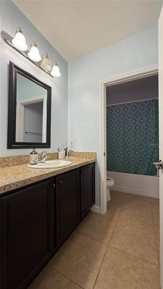 bathroom with tile patterned flooring, vanity, toilet, and a textured ceiling