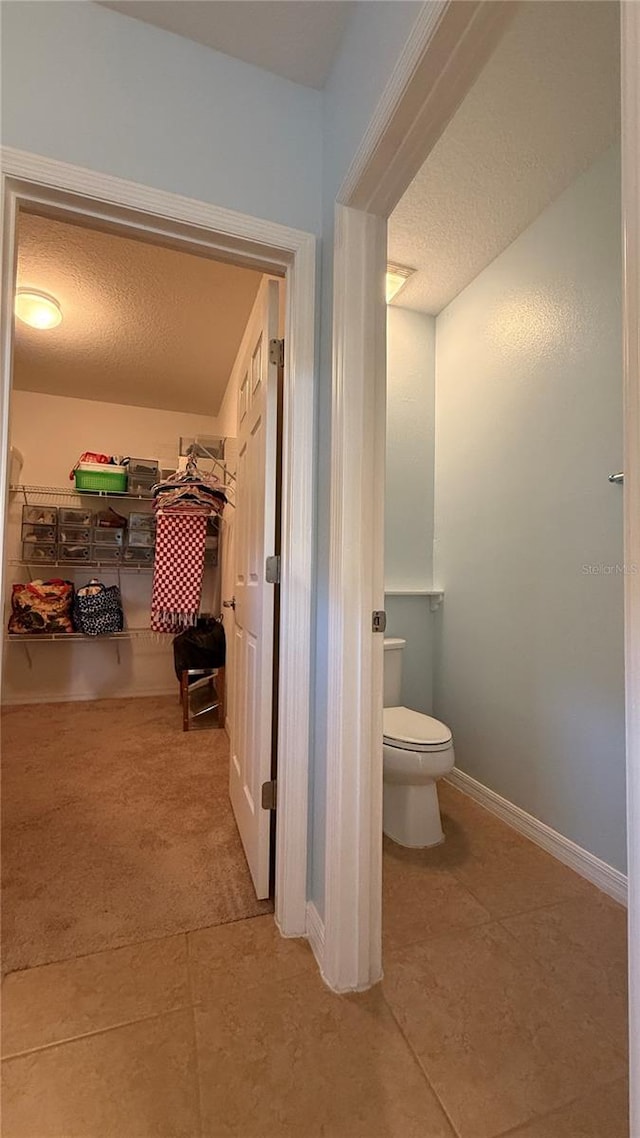 bathroom featuring tile patterned flooring, toilet, and a textured ceiling