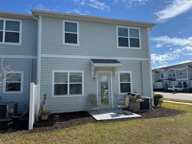 rear view of property with a lawn and central air condition unit