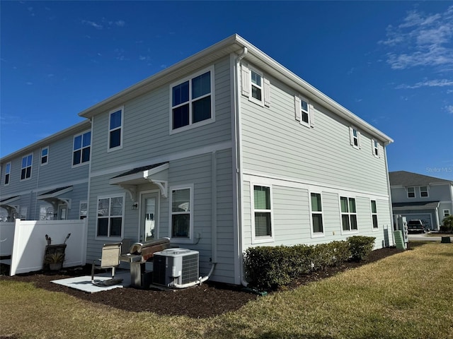 rear view of property with a lawn and central AC