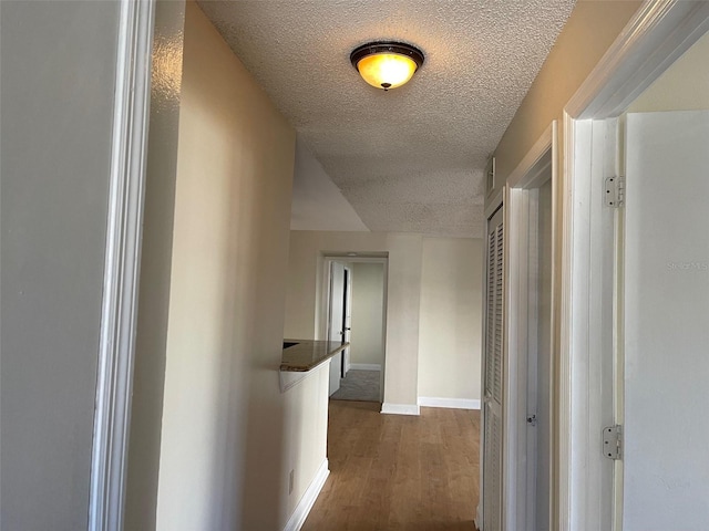 hallway with a textured ceiling and hardwood / wood-style flooring