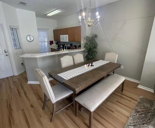 dining room featuring a chandelier, a textured ceiling, and light hardwood / wood-style floors